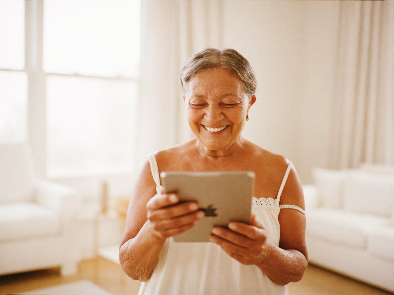 Persona mayor usando una tablet con confianza junto a una ventana con luz cálida